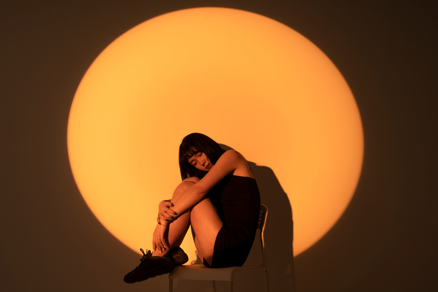 Hiver Caniculaire - Femme pensive assise devant un soleil orangé